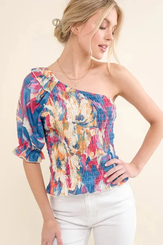 And The Why Allover Floral Print Smocked One Shoulder Blouse sold by Charming Charlie